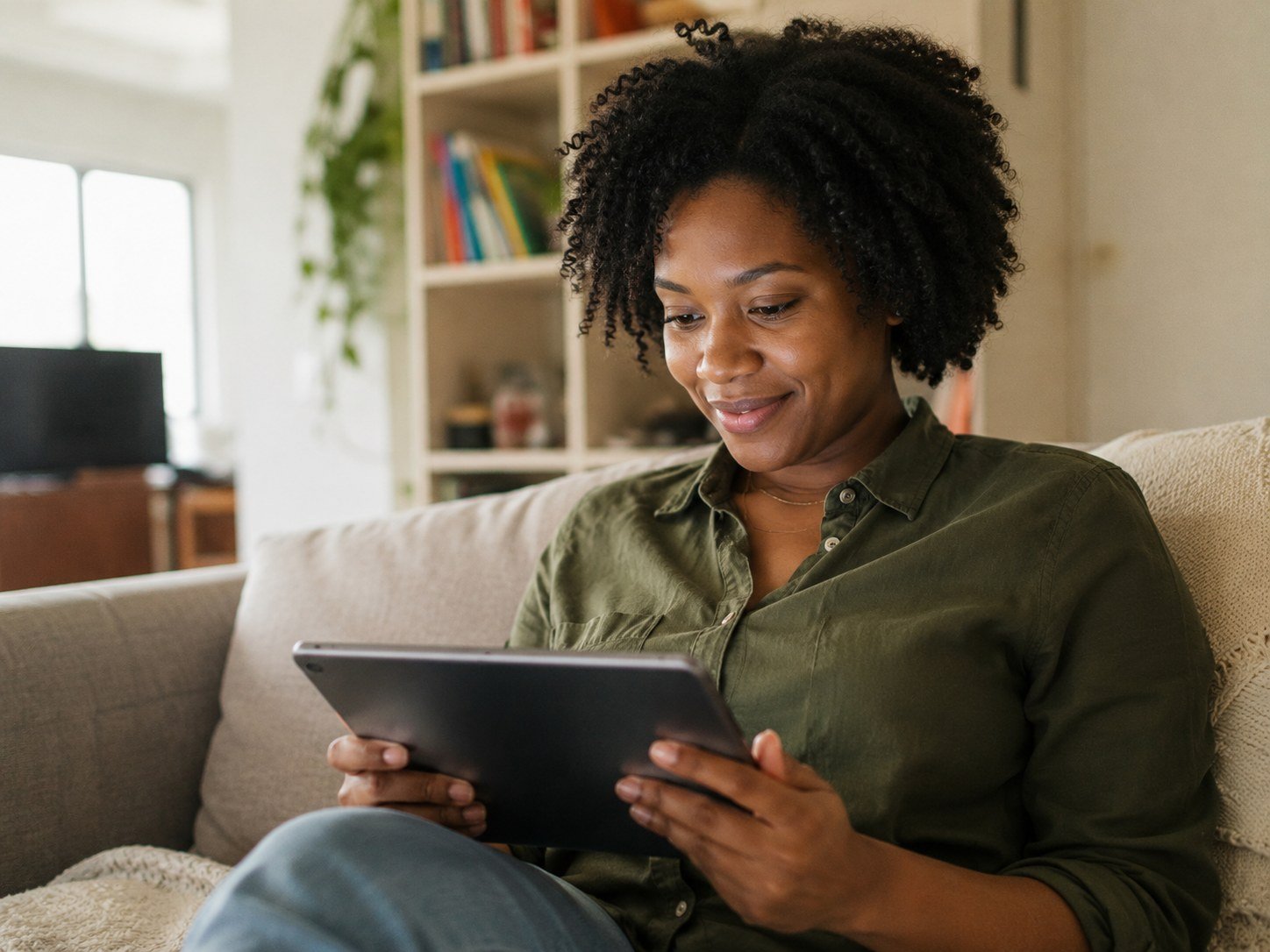 A woman relaxing on a sofa while using a tablet at home